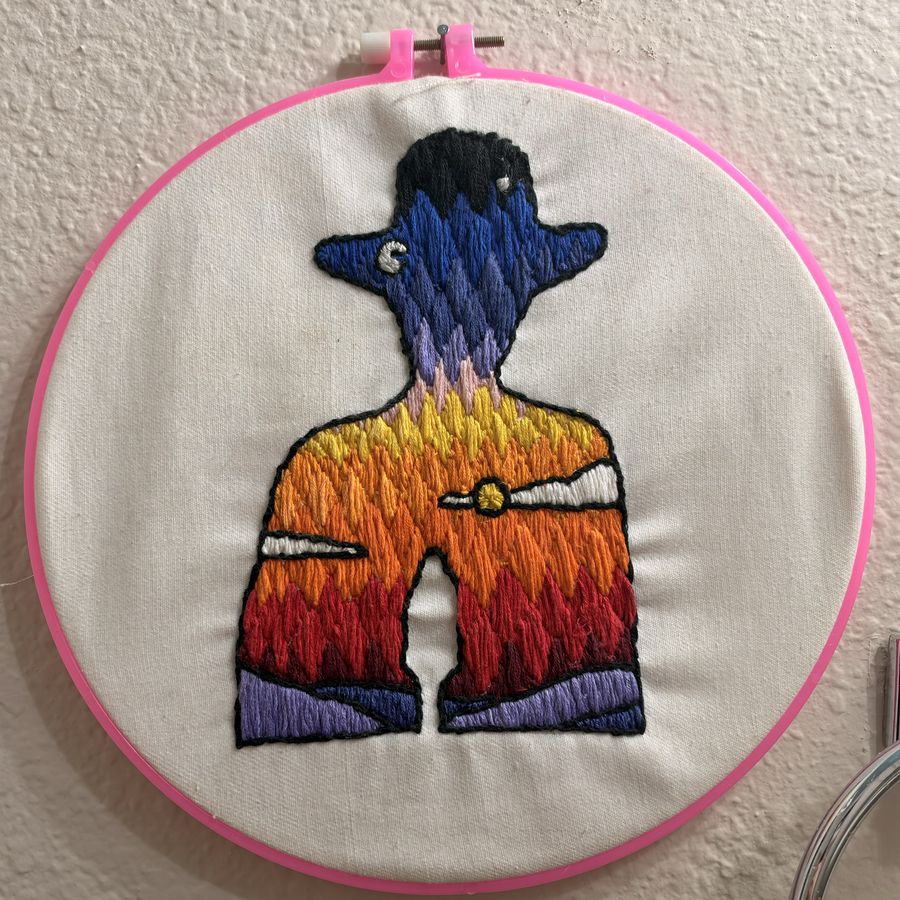 Hand embroidery of a cowboy silhouette filled with a sunset gradient, in a pink hoop