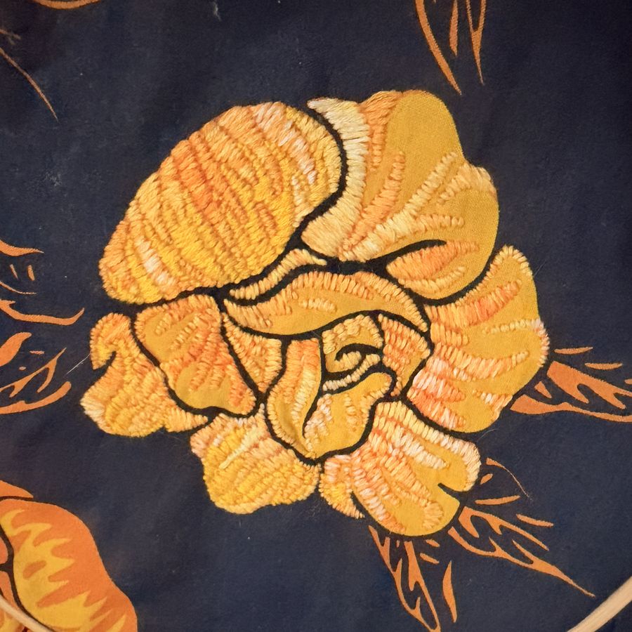 Close-up of a golden yellow rose embroidered over printed navy fabric