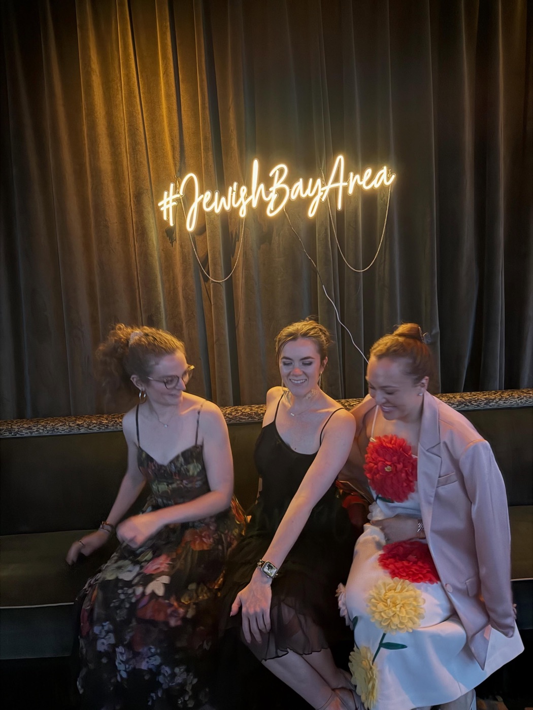 Ivey and two friends under a neon sign